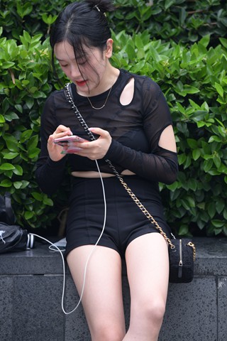 抓拍坐在花坛边的美腿女孩